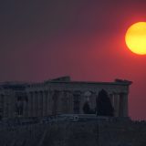 Smoke from a wildfire in the outskirts of the Greek capital covers the sun as it sets over the Parthenon temple atop of the ancient Acropolis ancient in Athens, Greece. (August 22, 2023)