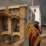 A man carries a saint Mary with Jesus icon to save it from a wildfire at Agia Paraskevi Christian Orthodox monastery in Acharnes a suburb of northern Athens, Greece. (August 23, 2023)